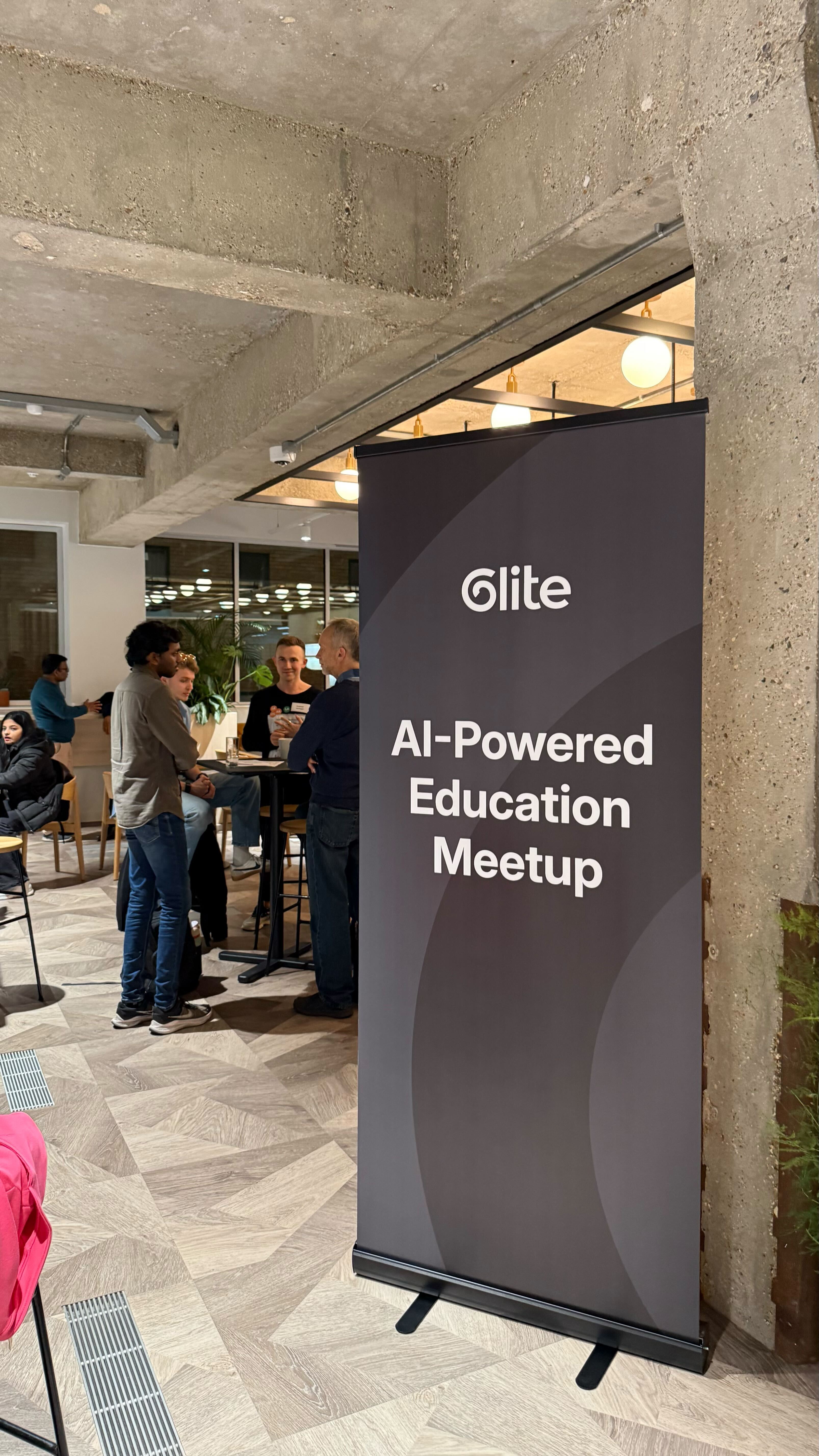 People talking beside the Glite AI-Powered Education Meetup banner.